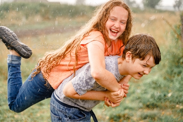 Happy children with piggyback riding playing in the rain