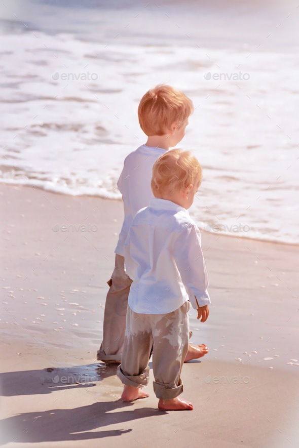 Two brothers standing at the edge of the ocean