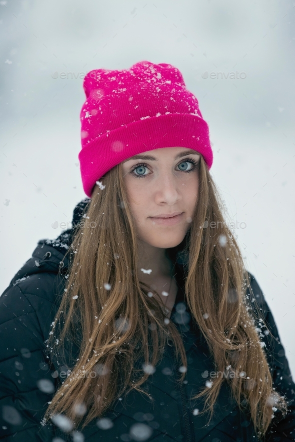 Portrait of a teenage girl wearing pink hat in the falling snow Stock