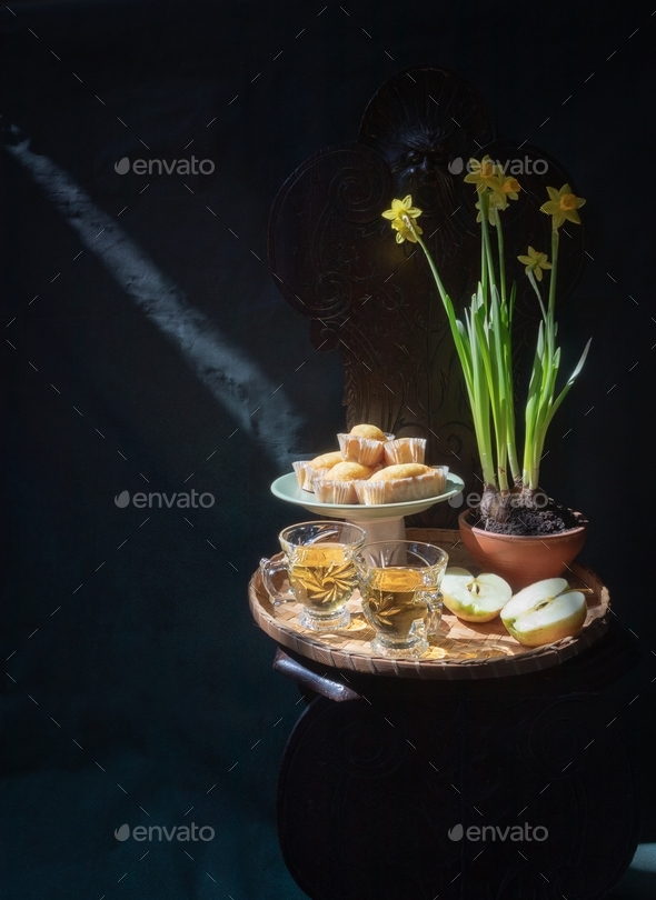 a ray of light falls on a platter of cakes on a chair. Daffodil pot. Light and shadow