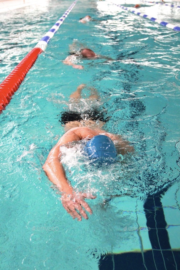 Sport swim training indoors, swimming in lanes in indoor pool. Fitness, strength and stamina.