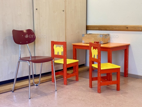 Doctors surgery waiting room, red and yellow small furniture in children’s play corner empty room.