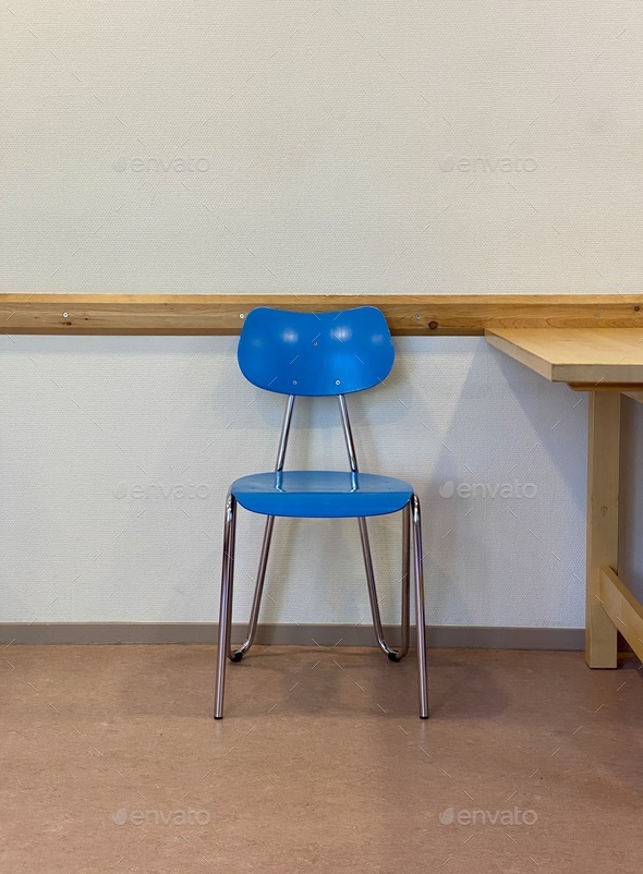 Doctors surgery waiting room with blue empty retro chair and wooden table. Conceptual wait image.