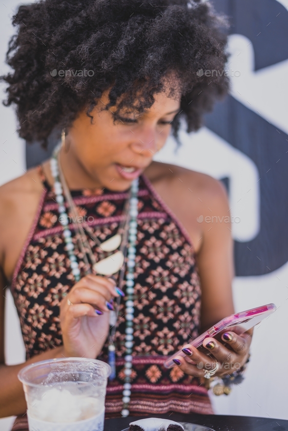 Black woman looking at phone at coffee shop