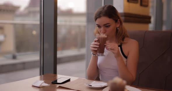 Beautiful Woman Drinks Cacao in Cafe
