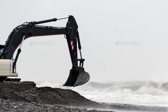 Excavator works on the seashore during a storm