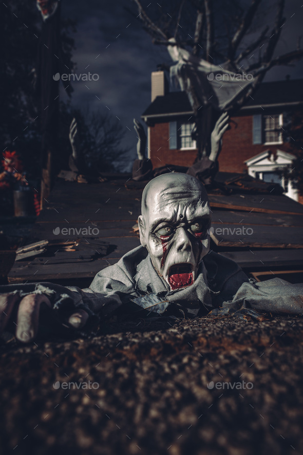 A terrifying zombie crawling out of the sewer drain in a Halloween yard display.