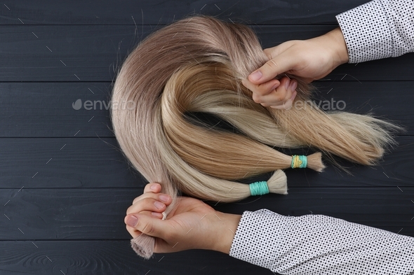 Top view of man’a hands holding hair sections for extension. Different types of hair.