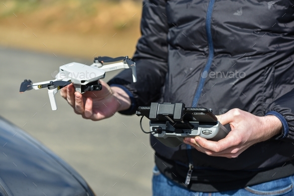 Pilot holds the Drone DJI Mavic Mini 2 and DJI remote controller after flight