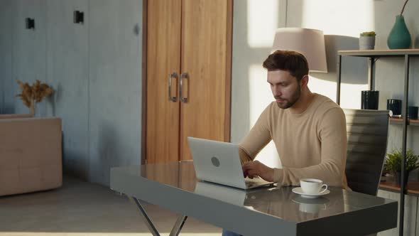 A successful man reacts emotionally to the news sitting on the desk in home office alt