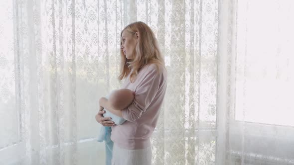 Newborn Baby Sleeps Tightly in His Mother's Arms. Mom Carefully Caresses Her Baby in Her Arms and alt