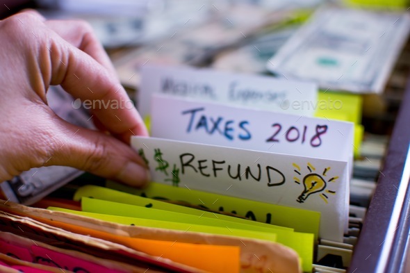 Tax files and tax refund files in a filing cabinet with woman going through tax records