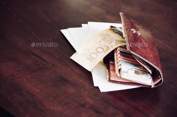 Canadian money cash in wallet on table with credit cards and envelopes