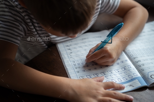Little boy of elementary age writing letters  - Stock Photo - Images