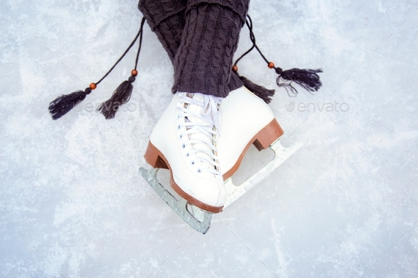 Legs shod with white figure skates. Beautiful leg pose on an ice rink
