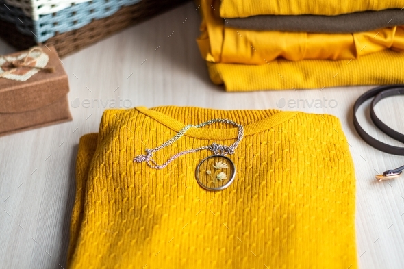 Accessory with a pendant with a dried flower behind a transparent glass on a yellow knitted sweater