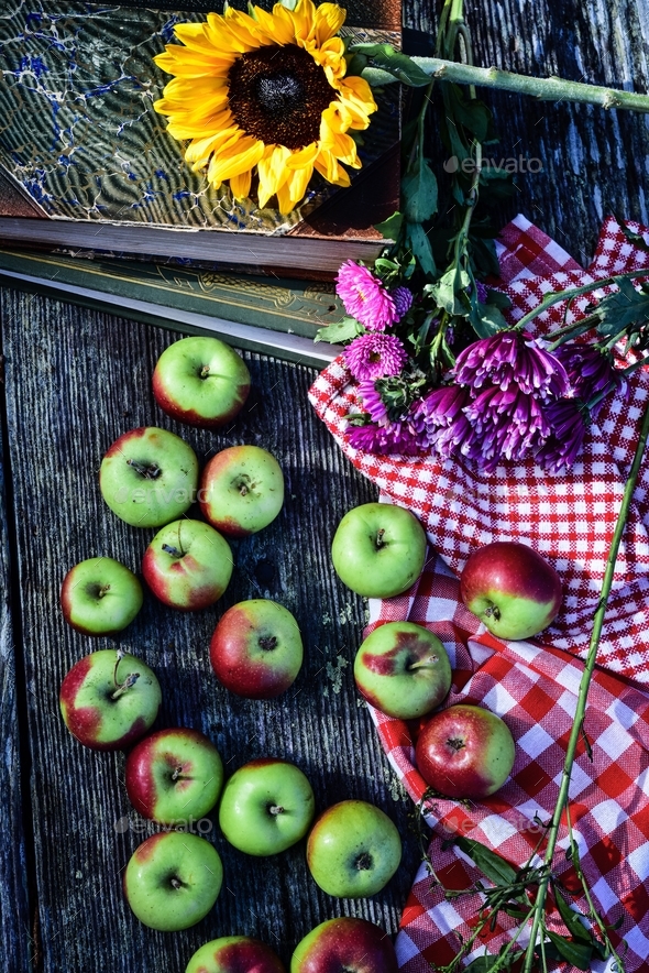 red and green Lady apples on rustic wood tabletop with red gingham check cloth
