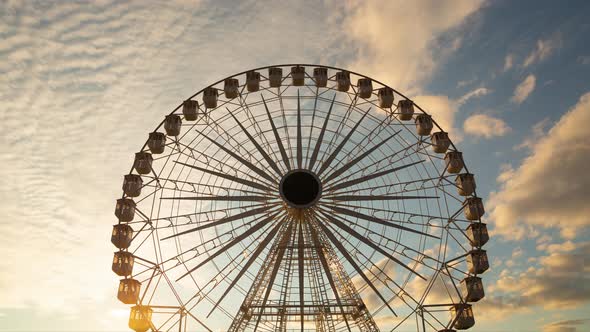 Ferris wheel silhouette - time lapse against orange clouds in the sky at sunset alt