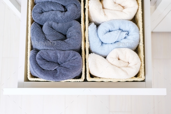 Rolled towels in boxes in dresser top view, space organization concept.