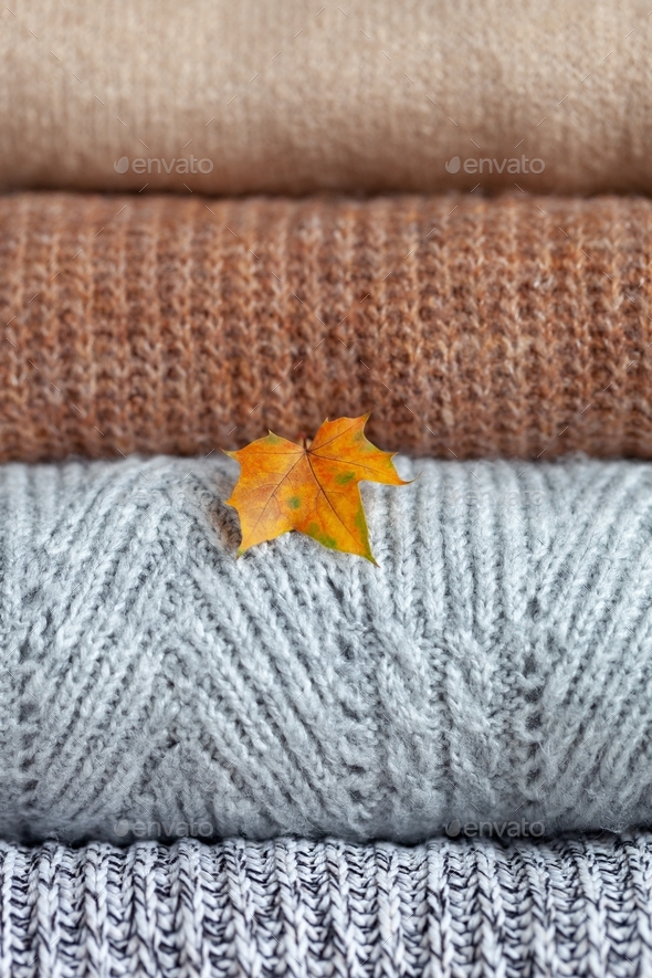 Stack of cozy knitted sweaters on a neutral background. Warm concept ...