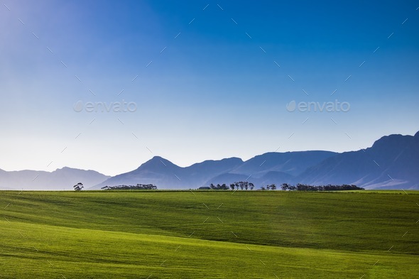 Farm in a field with mountains and blue sky. - Stock Photo - Images