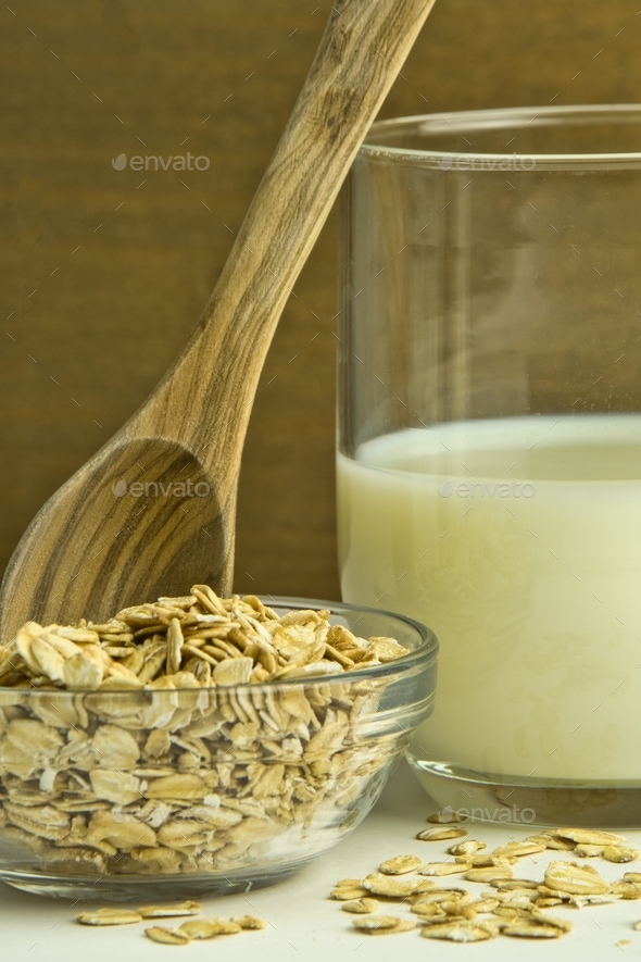 Oat flakes and oat drink in glass jars on wooden background. Healthy lifestyle and diet concept