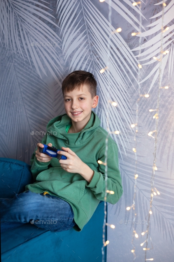 Boy on the couch plays video games using a controller.