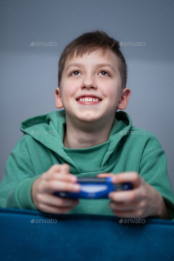 Boy on the couch plays video games using a controller at home.