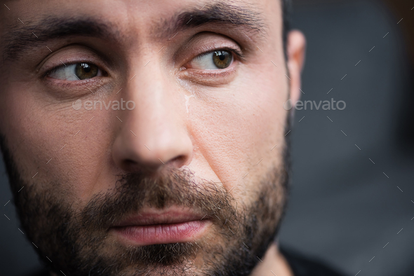 portrait of handsome bearded man crying and looking away