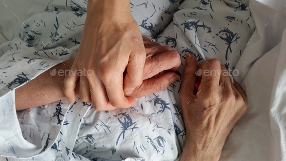 holding elderly family member\'s hand in hospital during end of life care