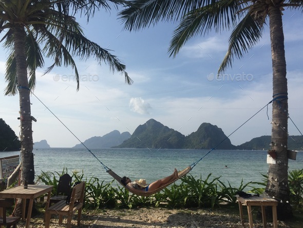 A woman relaxing on a hammock at the beach.