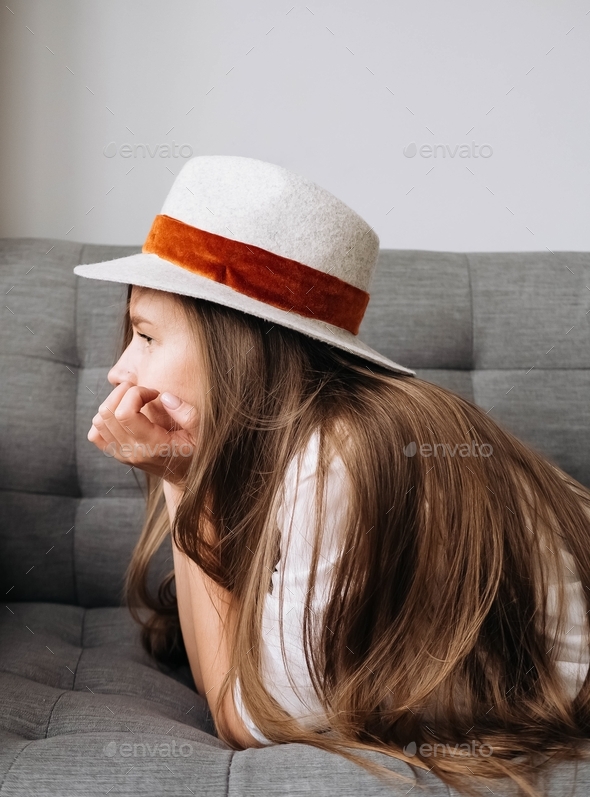 Bored girl lies on the couch and looks into the distance - Stock Photo - Images