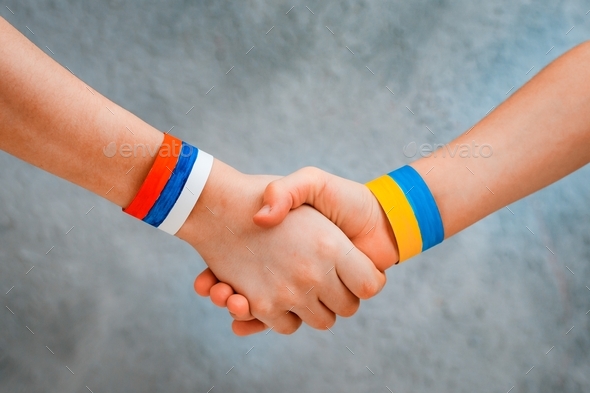 Reconciliation concept and handshake. Children\'s Hands with drawing flag of Ukraine and Russia