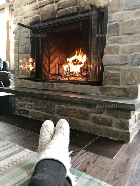 Roaring fire place in the distance with cozy covered feet in cream coloured socks
