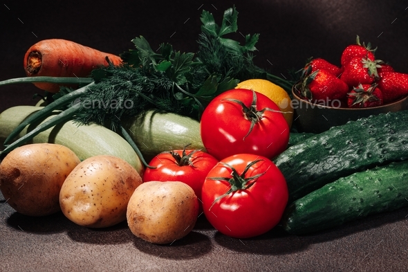 Fresh vegetables, fruits, berries and greens on a brown background still life