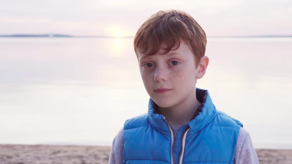 Cute Redhead Boy with Freckles By Sea at Sunset