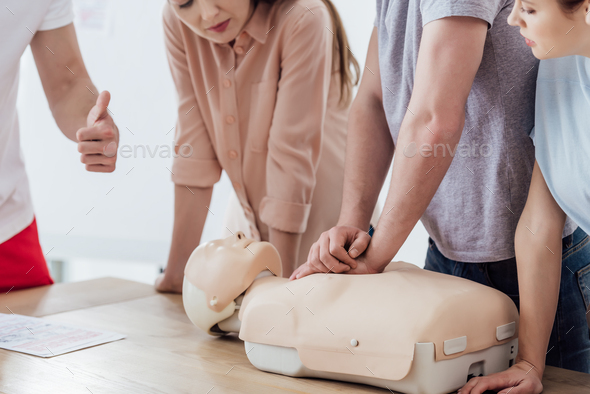 cropped view of man performing chest compression on dummy during cpr training class