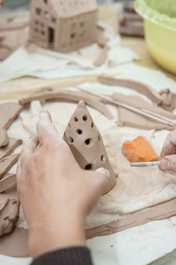 Women's hands knead clay, drawing elements of the product. Production