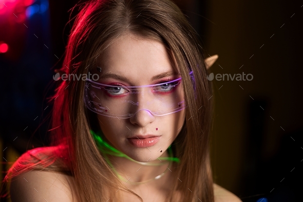 Cosplay girl in glasses with elf ears in coloured light