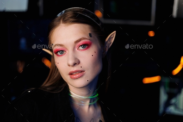 Cosplay girl with artistic make-up in glasses with elf ears in coloured light