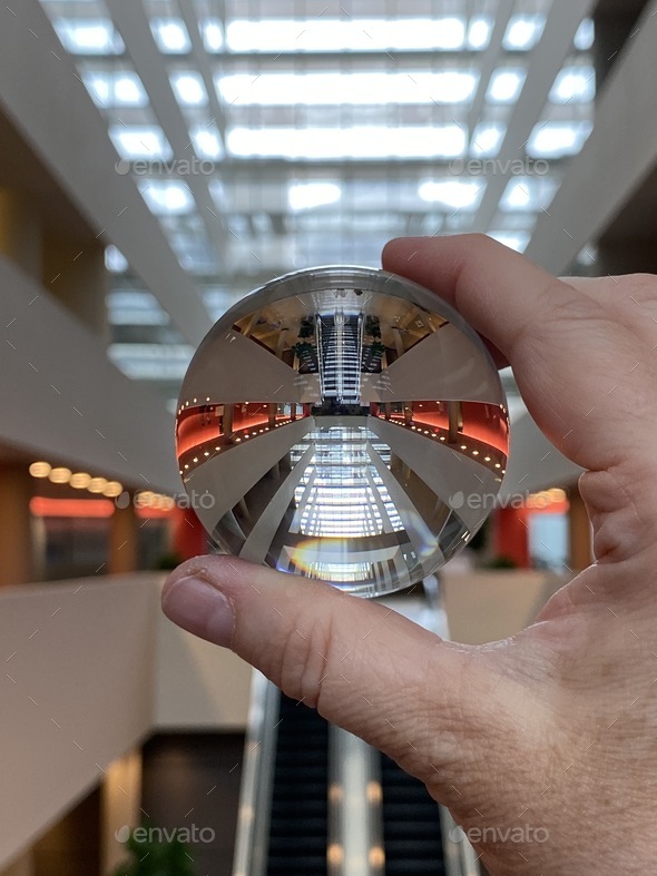 Escalator and glass ceiling as seen through a lens ball Stock Photo by