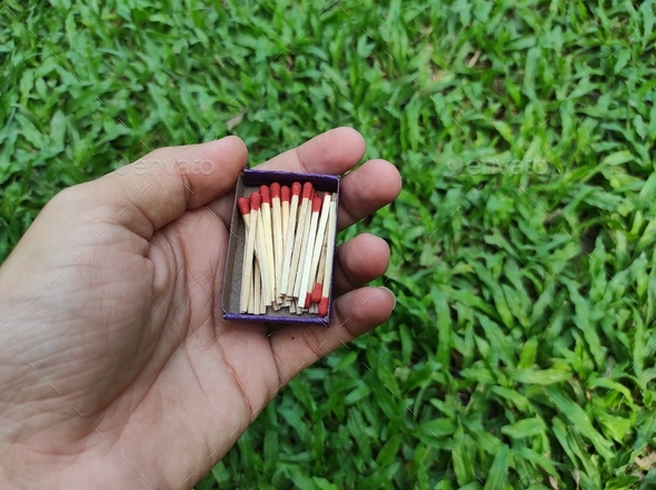 Full matchbox with matchstick or matches on hand with green grass
