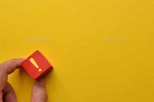 Exclamation mark concept. Wooden block with exclamation mark on yellow background.