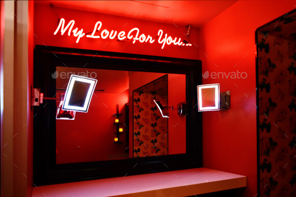 Ladies red bathroom is reflecting in mirror and neon words “ my love for you” on wall