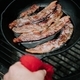 Cooking bacon in a cast iron skillet at a campsite.  - PhotoDune Item for Sale