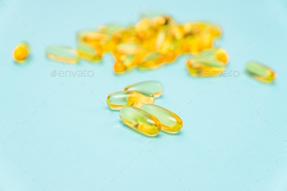 Omega 3 gel capsules on blue background. Food supplements for healthy living