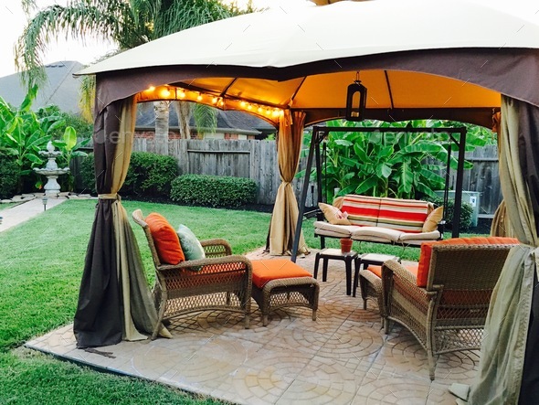 Outdoor covered gazebo with lighting and striking patio furniture; features stone fountain.