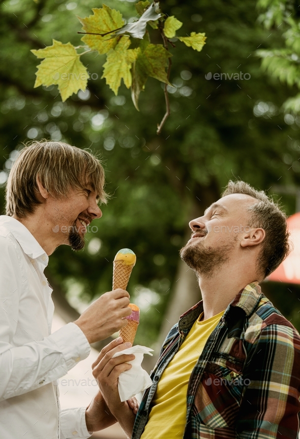 Gay couple on a date eating ice cream in the park - Stock Photo - Images