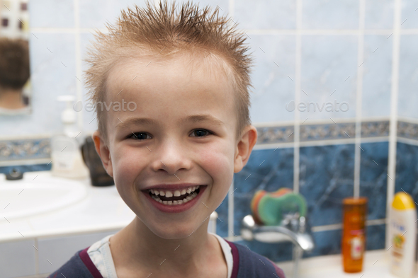 Portrait of a boy with wet hair after taking a shower of bath. Funny boy with crazy hairstyle.
