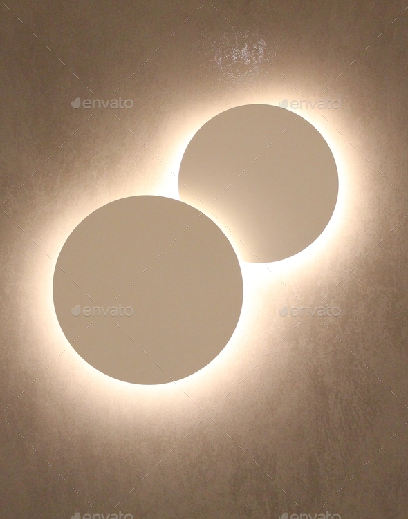 Glowing circular light fittings on a wall inside a shopping mall Stock